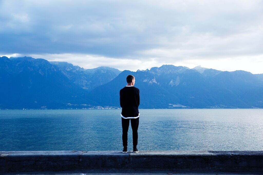 A man standing on the edge of a pier looking out at water.