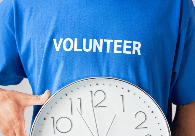 A person holding a clock with the word volunteer on it.